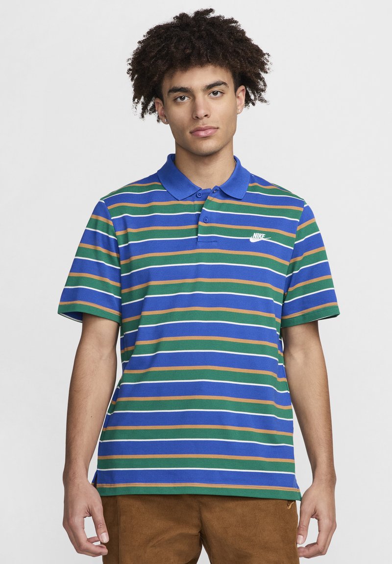 Dryžuotas Nike polo marškinėliai mėlynai, žaliai, oranžinei ir baltai. Turi apykaklę, tris mygtukus ir mažą baltą logotipą ant krūtinės.