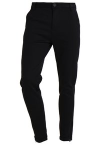 Pantalon noir sur mesure à coupe slim, en tissu lisse, avec passants pour ceinture, fermeture devant par bouton et chevilles zippées.
