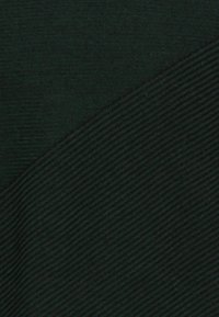 Mörkgrön textil med en ribbad yta på ena sidan och en slät finish på den andra, med en diagonal söm som delar de två områdena.