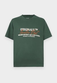 Zielona bawełniana koszulka z krótkim rękawem. Posiada biało-pomarańczowy tekst graficzny: "ORIGINALS™ Creative Dept. HOLMEN DISTRICT cph. DAILY BASICS."