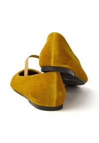 Gelbe Samt-Ballettschuhe mit einer spitzen Zehenpartie, einem Riemen hinten und einer flachen schwarzen Sohle. Glatte Textur mit einem weich matten Finish.