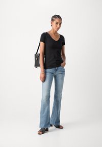 Black cotton t-shirt with a v-neck, light blue flared jeans, black handbag, and open-toed heeled sandals. Smooth textures and casual design.