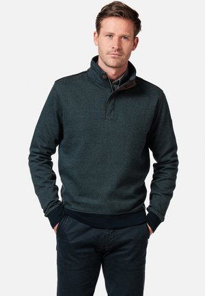 Donkerblauwe fleece pullover met een hoge kraag, ribbelmanchetten en -zoom, en een contrasterende bruine knoopdetail bij de hals.