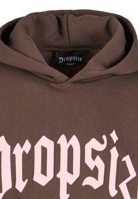 Brun hættebluse med et stort logo i lys pink skrift. Materialet er blødt, med en hætte med snor og et mærke, der angiver størrelse large.