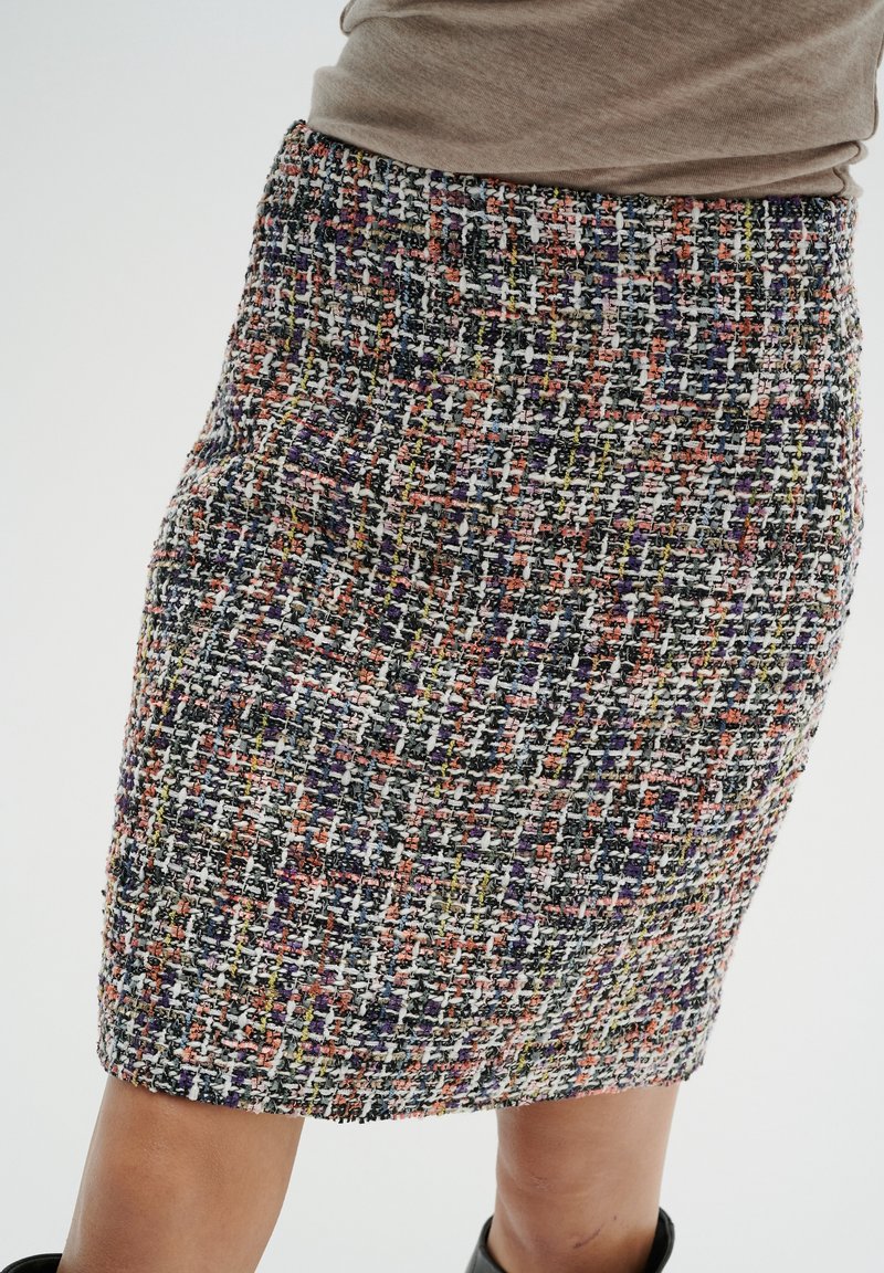 Falda lápiz tejida con un patrón de sarga multicolor, que presenta una mezcla de hilos morados, naranjas, amarillos y blancos. Acabado texturizado.
