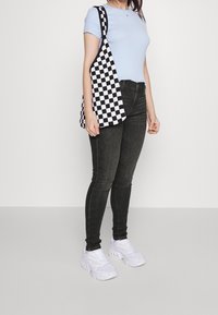 Ljusblåt fitted t-shirt, svarta skinny jeans, vita sneakers och en svart-vitrutig axelväska.