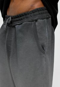 Grijze sweatpants met een elastische tailleband en trekkoord, voorzien van zijzakken en een gestructureerde afwerking. Machinegestikte details aanwezig.