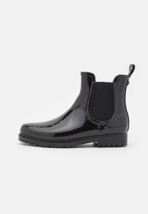 Bottine Chelsea noire brillante avec panneau latéral élastique, languette à l'arrière et semelle en caoutchouc à crampons.