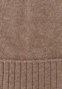 Brown knitted beanie made from soft material, featuring a ribbed cuff and subtle flecks of color throughout the fabric for added texture.