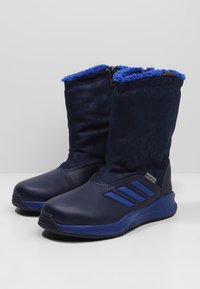 Námořnické boty s texturovaným svrškem, modrou Sherpa podšívkou a gumovými podrážkami. Obsahují tři modré pruhy po straně a zipové zapínání.