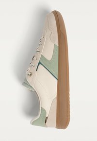 White and green leather sneaker with a textured finish, rounded toe, gum rubber sole, and metal eyelets for laces.