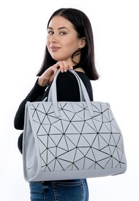 Grå geometrisk tote-väska med svarta accenter, tillverkad av hållbart material, med en strukturerad design och dubbla korta handtag.