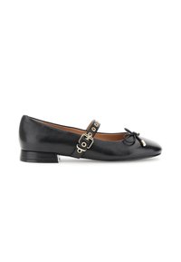 Scarpa piatta in pelle nera con tacco basso, cinturino con fibbia e occhielli dorati, e un piccolo fiocco sulla punta arrotondata.