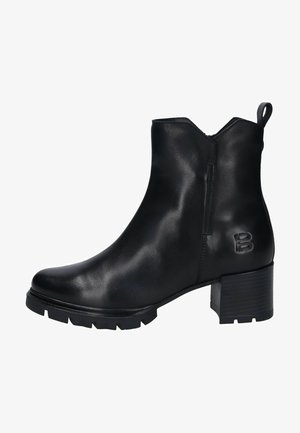 Botines negros de piel suave, con tacón cuadrado, suela dentada y una lengüeta en la parte trasera. Diseño monocromático con logo grabado.