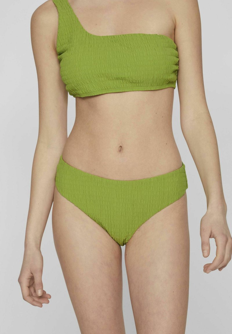 Bikini de color verde con textura que presenta un top asimétrico y una parte de abajo alta a juego, mostrando un patrón acanalado y material elástico.