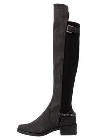 Bota negra por encima de la rodilla con parte delantera de ante, parte trasera elástica, tacón bajo y detalle de cadena plateada en el tobillo.