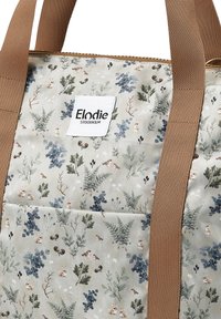 Borsa in tessuto con sfondo beige chiaro e motivo floreale che presenta conigli e felci, completata da manici in tessuto marrone e una patch con il logo.