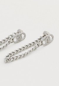 Sudraba ķēdes auskari ar gludu virsmu, kuros ir divi savienojumi, rotāti ar caurspīdīgiem rhinestones, un droša aizdare.