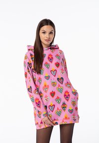 Rosa Kapuzenpullover mit einem lebhaften Herz- und Flammenmuster in verschiedenen Farben. Weicher Stoff mit einem lockeren Schnitt und einer Vordertasche.