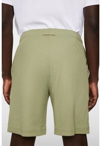 Oliwkowe szorty wykonane z miękkiego materiału, z elastycznym paskiem w talii oraz bocznymi kieszeniami, zapewniające komfortowy, luźny krój.