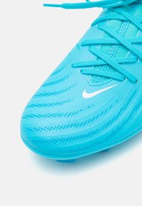 Scarpe da calcio turchesi con tomaia testurizzata e motivi a onda, lacci piatti e logo Nike bianco di lato.