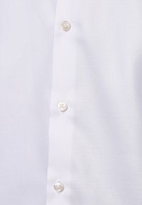 Weißes Hemd mit Knopfleiste aus strukturiertem, gewebtem Stoff. Verfügt über vier runde Perlmuttknöpfe entlang der Knopfleiste und sichtbare Nähte.