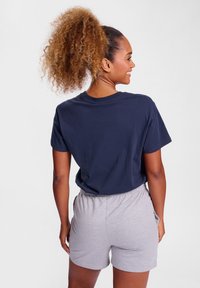 Marineblå bomull T-skjorte med løs passform, sammen med lysegrå bomullsshorts med elastisk midjebånd og sidelommer.