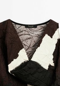 Robe col en V avec tissu froissé en blocs de couleurs noir, marron et blanc, montrant l’étiquette Massimo Dutti à l’intérieur du col.
