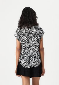 T-shirt à manches courtes avec un motif abstrait noir et blanc. Fabriqué en tissu léger avec un ourlet arrondi et une coupe décontractée.