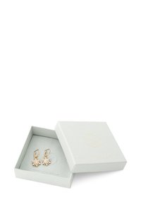 Goldfarbene Ohrringe mit floralem Design, das einen zentralen klaren Edelstein zeigt, präsentiert in einer hellgrauen, strukturierten Schmuckschatulle.