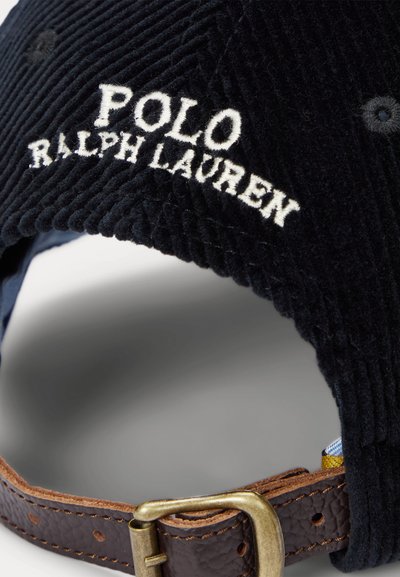 Gorra Polo Ralph Lauren de pana negra con logo bordado en blanco y correa de cuero marrón ajustable con hebilla dorada.