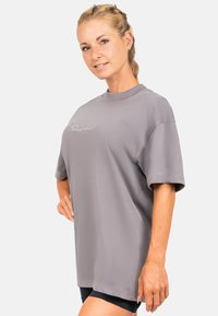 Overdreven T-shirt met korte mouwen in lichtgrijze katoenmix, met een ronde hals en een subtiel wit logo op het linkerborstgebied.