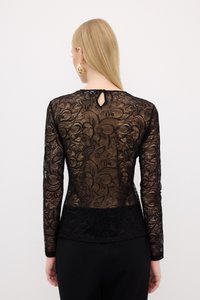 Top in pizzo nero con maniche lunghe, caratterizzato da motivi floreali, orlo nero solido e dettaglio a forma di chiave sul retro. Texture morbida con un design aderente.