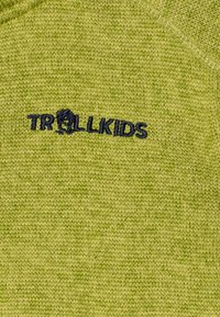 Grüner Strickpullover mit TROLLKIDS-Logo in Marineblau. Die Textur ist weich mit einer glatten Oberfläche und zeigt einen lebhaften Grünton.