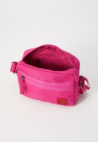 Borsa a spalla di stoffa rosa con chiusura a zip, tasca frontale con zip e foderatura interna testurizzata. Presenta un piccolo etichetta con il marchio.