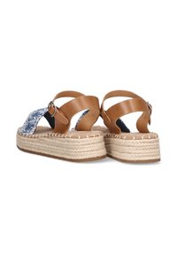Sandalias de cuero marrón con correas de tela azul estampada. Base de plataforma con detalles de yute trenzado y un tacón redondeado. Cierre de hebilla en la correa.