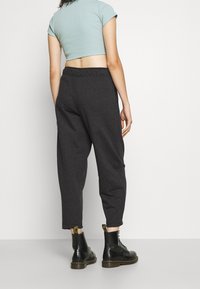 Grå, avsmalnande sweatpants gjorda av mjukt tyg, med resårmidja och sidofickor, i kombination med svarta ankelstövlar.