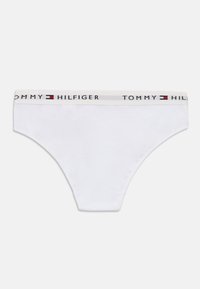 Balti kokvilnas plānas apakšbikses ar mīkstu jostu, kurā ir melnas, sarkanas un zilas "TOMMY HILFIGER" logo. Minimālistisks dizains, gluda tekstūra.