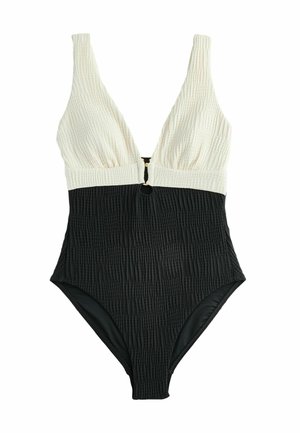 Maillot de bain une pièce noir et crème avec texture cannelée, décolleté en V profond, larges bretelles et un détail en métal doré au centre de la poitrine.