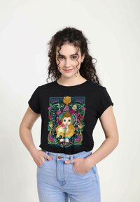 Sort t-shirt med et farverigt grafik af en karakter omgivet af roser og figurer, med oprullede ærmer og en afslappet pasform.