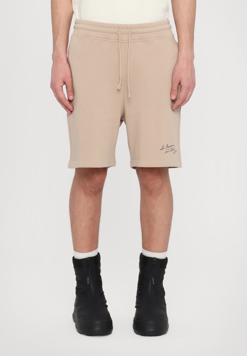 Shorts en coton beige avec une taille élastique et un cordon de serrage. Comprend des poches latérales et un petit logo brodé à l'avant.