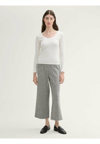 Witte ribgebreide top met lange mouwen, gecombineerd met grijze wijde wolmix broek met een subtiel visgraatpatroon. Zwarte loafers maken de look af.