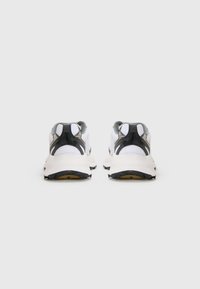 White athletic shoes with a black heel and grey accents, featuring a mesh upper, textured materials, and a rubber sole with traction lugs.