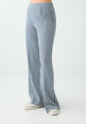 High-waisted, wide-leg pants with a blue and white houndstooth pattern worn with white sneakers on a light background.
