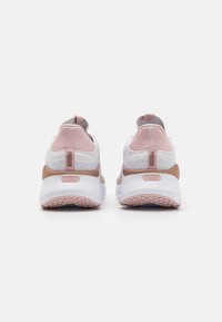 Un paio di sneakers bianche e rosa con suole testurizzate e etichetta "SOFTRIDE" sul tallone, viste da dietro.