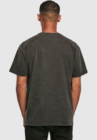 Donkergrijze katoenen t-shirt met een relaxte pasvorm, korte mouwen en een ronde hals. Heeft een vervaagde textuur en zichtbare stikseldetails.