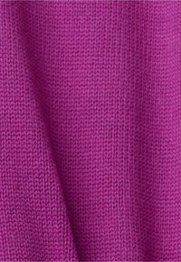 Gros plan sur un tissu tricoté violet vif montrant une texture douce et un motif de points serrés avec de légers plis.