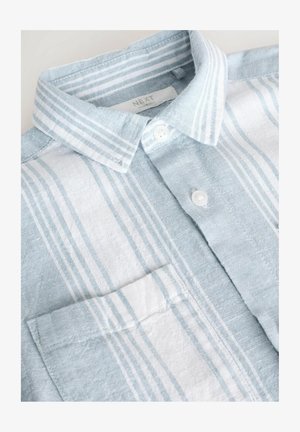 Hele helesinine ja valge triibuline särg, mis on valmistatud kootud kangast. Särgil on krae, nööbiga eesmine osa ning väike rinnakott. Sile tekstuur.