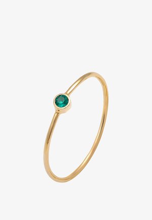 Anillo de oro con una banda delgada, que presenta una piedra preciosa redonda de color verde esmeralda engastada en un bisel pulido. Superficie suave con un diseño minimalista.