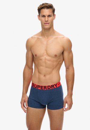 Blaue Boxer-Breve mit einem roten elastischen Bund, auf dem der Schriftzug "SUPERDRY" zu sehen ist. Hergestellt aus weichem Stoff mit einer engen Passform, zeigt ein einfarbiges Design.